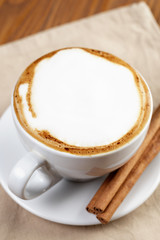 cup of fresh hot cappuccino with cinnamon sticks