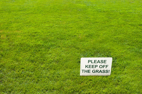 White Please Keep Off The Grass Sign On Green Grass.