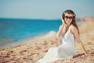 Fototapeta na wymiar Portrait of a beautiful woman on the beach listening to music