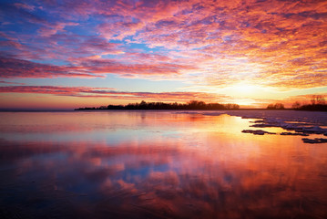Fototapeta na wymiar Winter landscape with lake and sunset fiery sky.