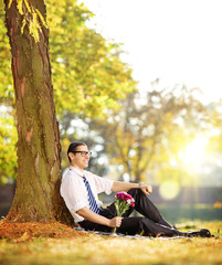 Handsome guy with a bunch of flowers in a park  on a sun