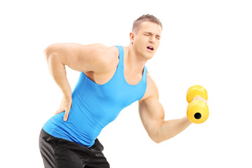 Young male athlete with back pain lifting a dumbbell