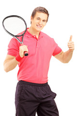 Young smiling man holding a tennis racket and giving thumb up