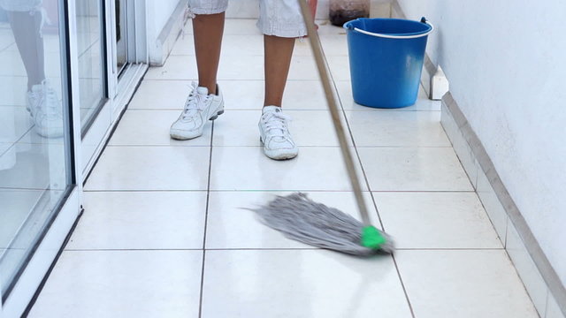 A young woman mopping the floor