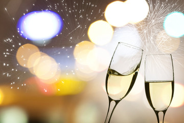 Glasses with champagne against fireworks and clock