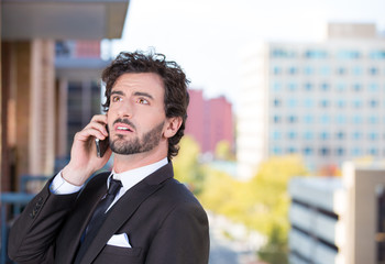 Businessman talking on a phone, on a balcony of his apartmentt