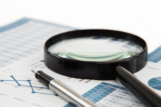 magnifying glass and pen over graph