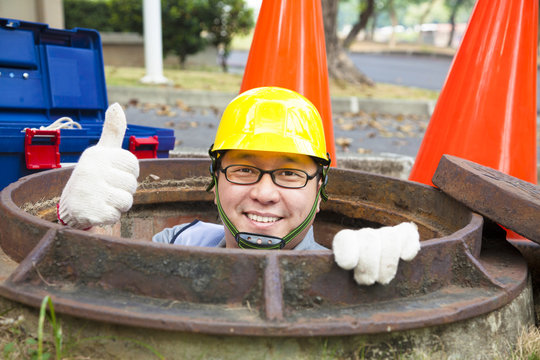 sewerage worker in the manhole with thumb up
