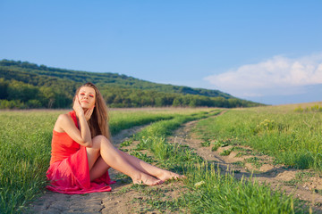 Portrait of a woman in red on a background of sky and grass