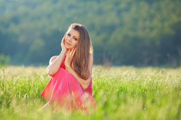 Portrait of a woman in red on a background of sky and grass