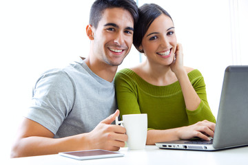 Happy young couple browsing internet at home