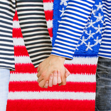 Man and woman holding hands together against US flag