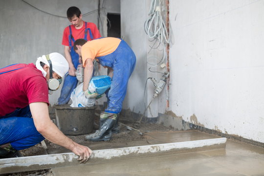 workers in construction room poured concrete floor