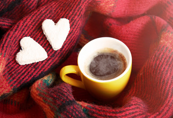 Coffee cup and two heart cookies at red rug