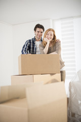 smiling couple leaning on boxes in new home