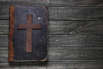 Old book and cross on wooden table