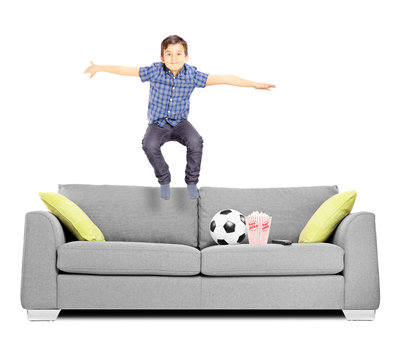 Happy Little Boy Jumping On A Sofa