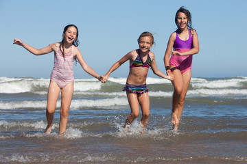 three happy girls running out of ocean