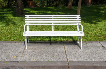 White bench in lush garden or park