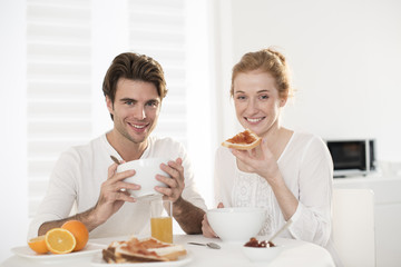 Obraz na płótnie Canvas young couple takes breakfast in kitchen