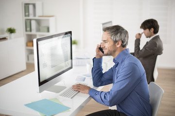 Obraz premium businessman at phone watching his computer