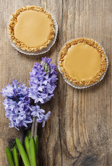 Toffee tarts on wooden table, violet hyacinth flower in the back