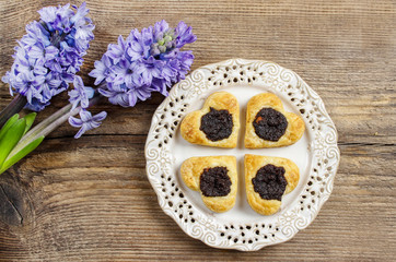Poppy seed cookies in heart shape on wooden table, hyacinth flow