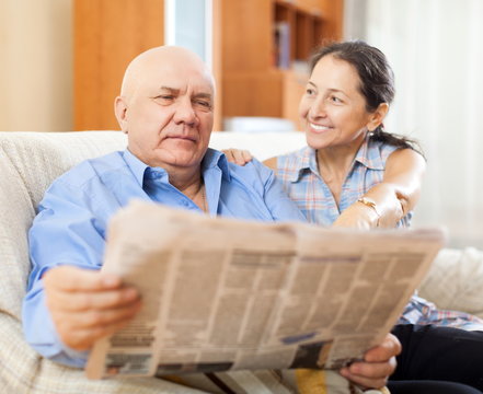 Portrait of laughing mature woman and elderly man with newspaper