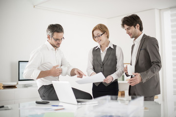 three colleagues speaks about business at office