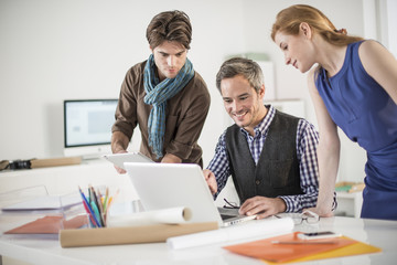 team discusses about a work project around a computer