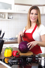 young modern housewife cuts red cabbage at home