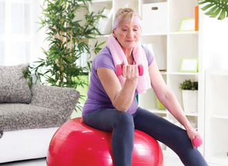 happy senior woman sitting on gym ball, and exercise with dumbbe
