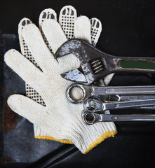 wrenches spanners plumbing and mechanic glove on dark metal back