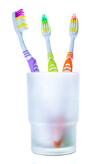 Three colorful toothbrushes in glass