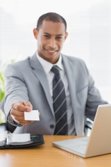 Well dressed man handing his business card at office desk