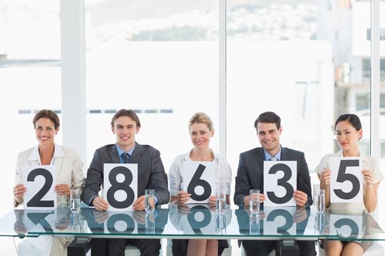 Group of panel judges holding score signs