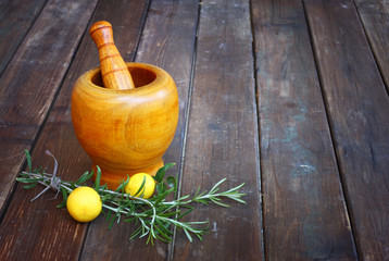 fresh rosemary herbs in wooden pestle and mortar on wooden table