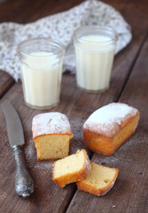 Small homemade muffins on a brown table with glasses of milk