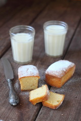 Small homemade muffins on a brown table with glasses of milk