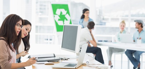 Naklejka premium Artists working at desks with recycling sign in background at of