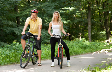 Attractive happy couple on a bicycles in a countryside
