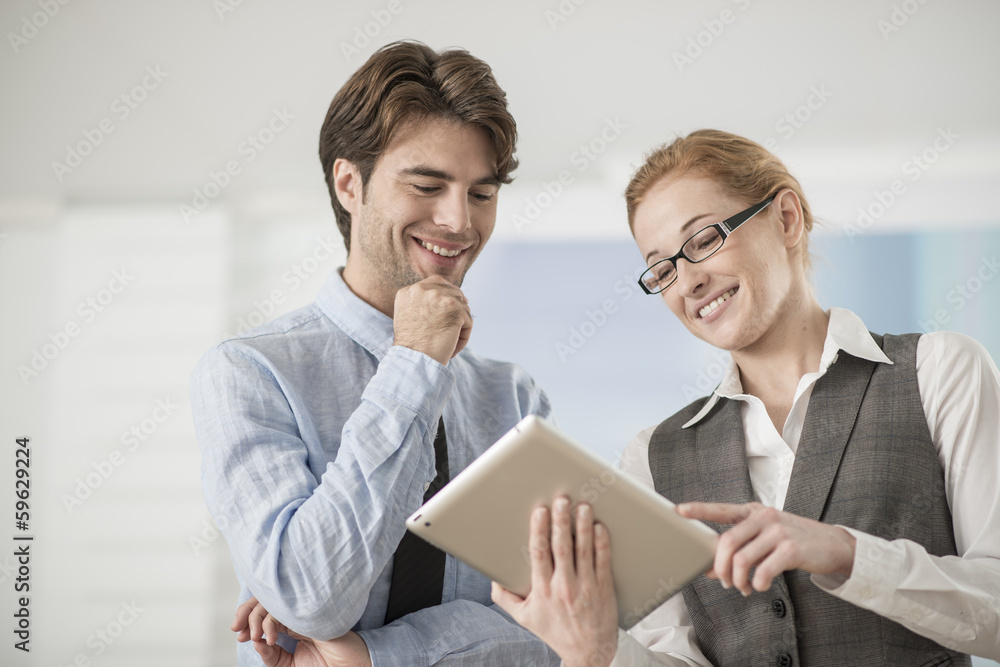 Wall mural two colleagues discuss around a digital tablet