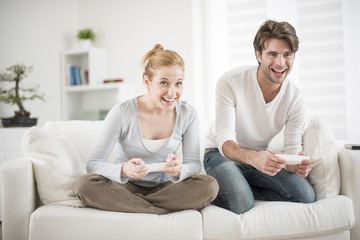 cheerful couple play to video game on a couch