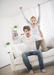 Cheerful couple watching football game on tv
