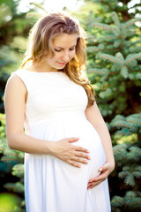 Fototapeta premium Young healthy beauty pregnant woman outdoors. A girl with a tumm
