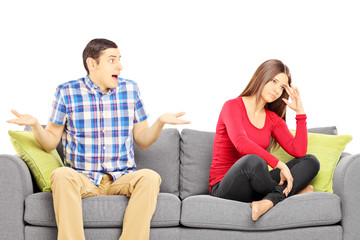 Young heterosexual couple sitting on a sofa during an argument