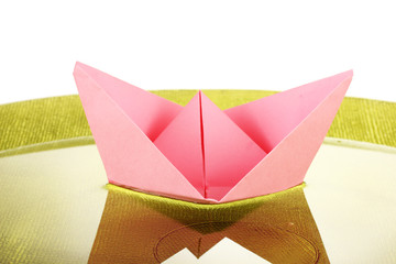 Color paper ship in water on green plate, close-up