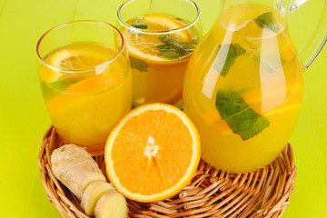 Orange lemonade in pitcher and glasses on wooden table close-up