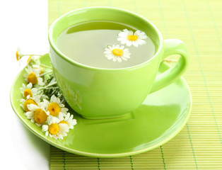 Cup of herbal tea with wild camomiles and mint, isolated