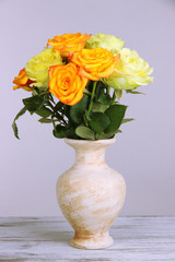 Beautiful bouquet of roses in vase on table on gray background